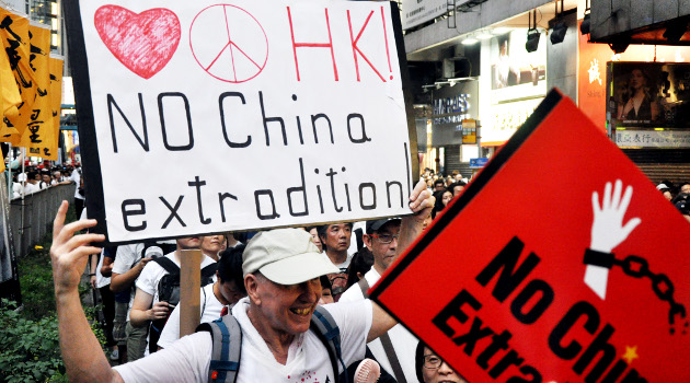 「NO China extradition」と書かれたプラカード掲げながらデモする外人男性